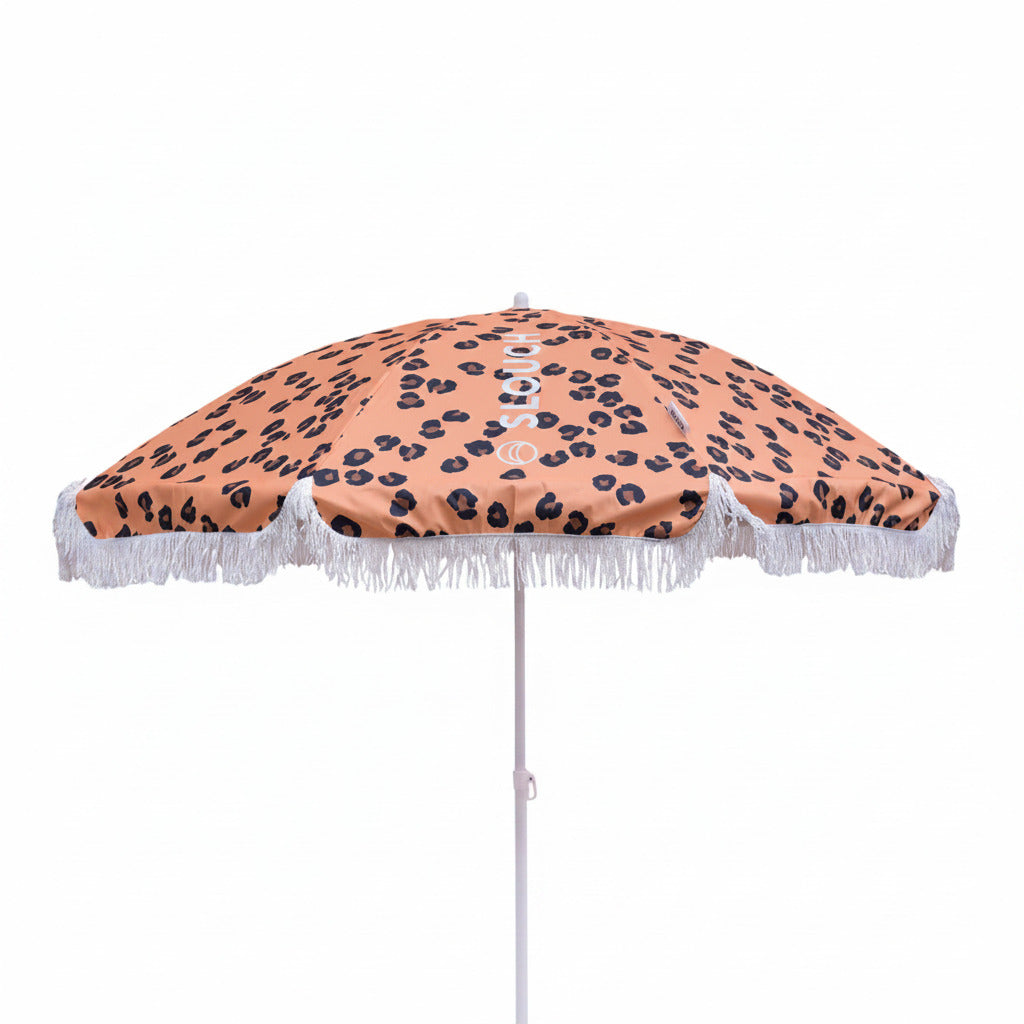 Beach umbrella with leopard print design and white fringe on a white background