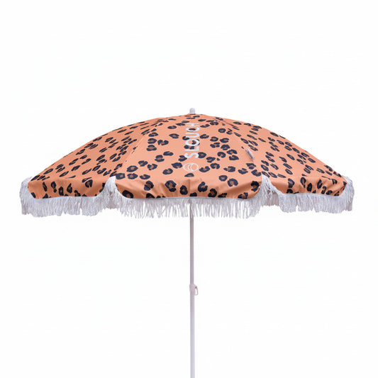 Beach umbrella with leopard print design and white fringe on a white background